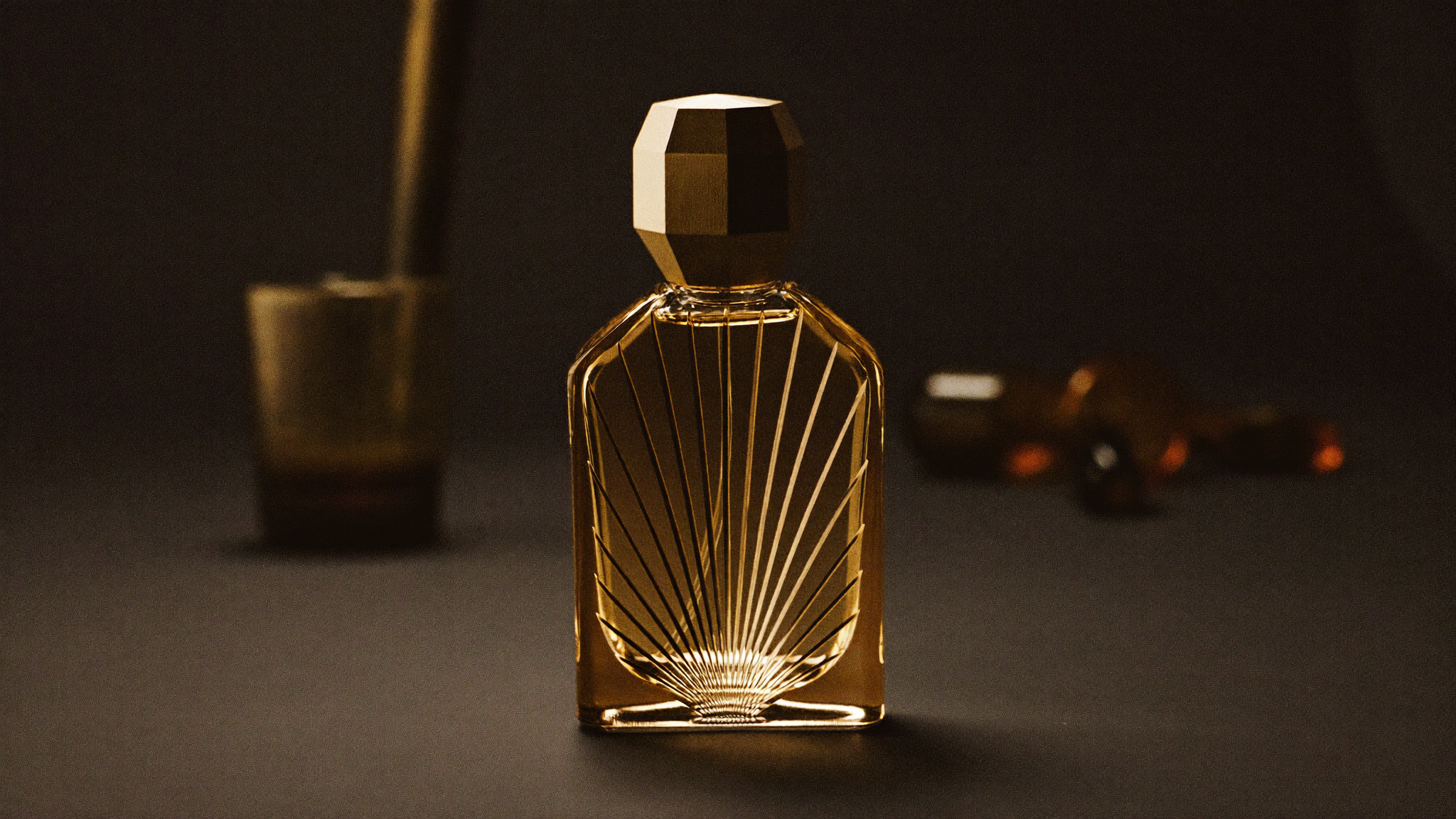 Skulpturel ravfarvet parfumeflaske med facetteret messingtop, foran en mørk art deco-solstråle